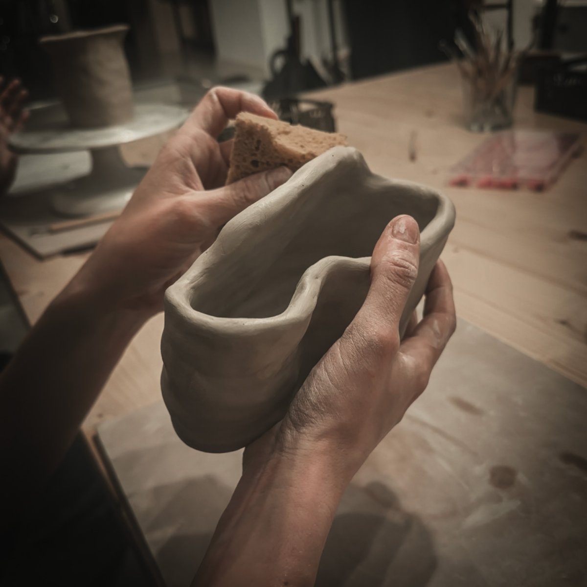 Mani che modellano un pezzo in argilla con la tecnica del colombino durante un corso Pottery Afterwork.
